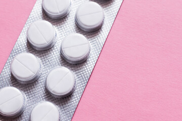 close up view of blister pack with white round shape pills isolated on pink.