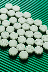 close up view of round shape medication on textured green background.