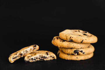 Close up view of cookies with chocolate chips on black background.