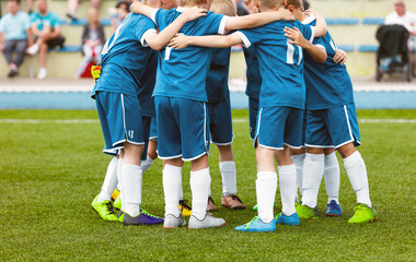 Motivated youth soccer team cheering on court. Players huddling in a circle on the field. Football captain talking to a group of soccer players. Happy football team in a circle © matimix