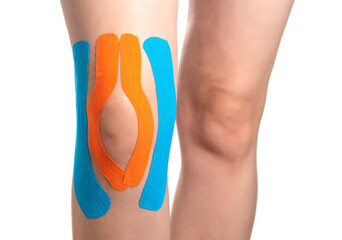 knee joint fixed with blue and orange kinesiological tape, close-up. Taping muscles and ligaments...