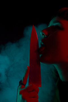A gothic girl with a knife in smoke with dark background