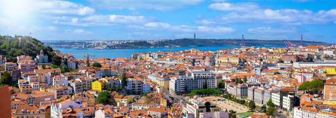 Naklejka na ściany i meble Panoramic view of the cityscape of Lisbon, Portugal, with Sao Jorge Castle and the red roofes of the Alfama district until the Tagus river on a sunny day