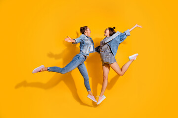 Fototapeta na wymiar Full length of two overjoyed people jumping raise opened hands hug isolated on yellow color background