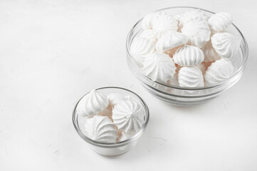 two glass vases of different sizes with French meringue dessert on a gray background, copy space.