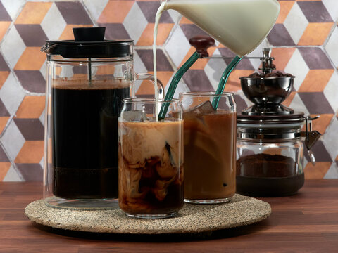 Making cold brew coffee with milk in a french press, also known as a cafetière, coffee press, or coffee plunger
