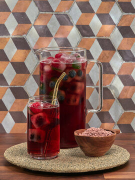 A jug and a glass of iced fruit tea made from instant tea granules