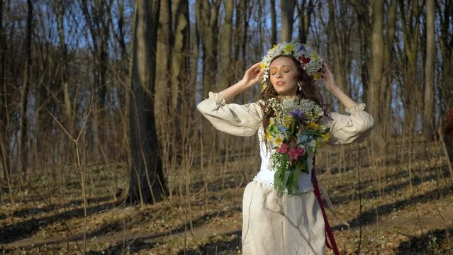 Girl in a wreath of flowers walks in the woods. Ancient Ukrainian embroidered dress. Ukraine.