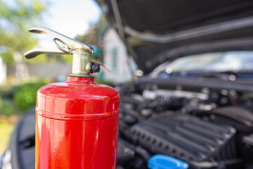 A car powder fire extinguisher is in a car with an open hood. The concept of modern fire...