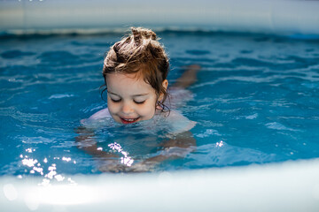 A little girl is in the pool and drinks water from the pool. The concept of summer holidays and indigestion and diarrhea in the summer
