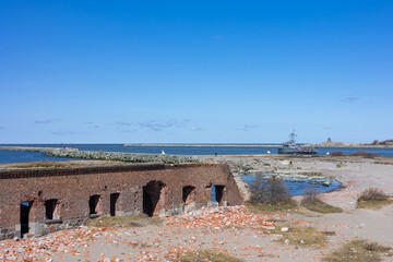 View from a ruined fort on the seashore to a warship in Baltiysk, Kalinigrad region, Russia, near the Baltic sea.
