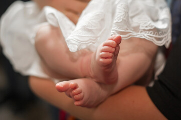 The legs of a small child close-up.
The sacrament of the baptism of a child in the church.