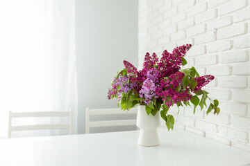 A bouquet of lilacs on a white table in a white kitchen