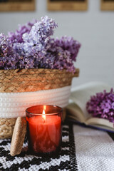 Obraz na płótnie Canvas Wicker basket with lilacs, a candle, an open book on the table.Good morning concept
