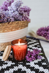 Obraz na płótnie Canvas Wicker basket with lilacs, a candle, an open book on the table.Good morning concept