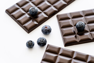 Close up view of blueberries and chocolate bars on white background.