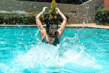 Woman swimming, splashing, and floating in pool. 