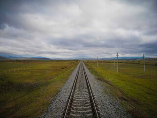 Fototapeta na wymiar Straight single train track leading in the vast tundra of Siberia on the trans siberian railway.