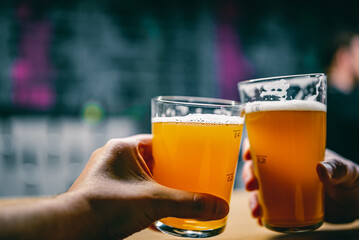 two glass of beer in man hand. Beer glasses clinking in bar or pub