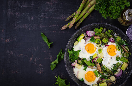 Fried eggs with asparagus, leeks, spinach and mushrooms. Useful breakfast. Top view, overhead