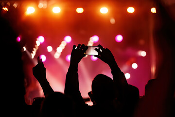 Fototapeta na wymiar Hand with a smartphone records live music festival, Taking photo of concert stage, live concert, music festival.