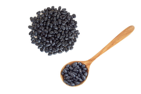 Closeup black beans seeds wooden spoon on white background, healthy food concept