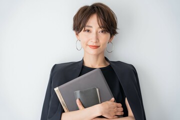 手帳とパソコンを持つ日本人女性・カメラ目線