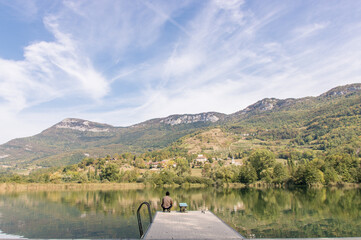 personne assise au bord d'un lac en été devant les montagnes des alpes à Saint-Jean-de-Chevelu en france