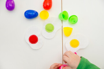 Happy Easter theme. Kid sorting eggs and learning colors. Montessori format task for kids...