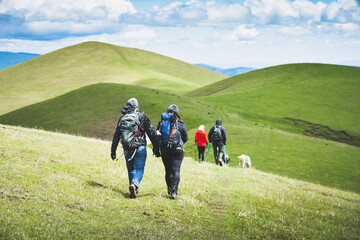 Caucasian young couple hike downhill on caucasus mountains trail in scenic nature. Work hard lose...
