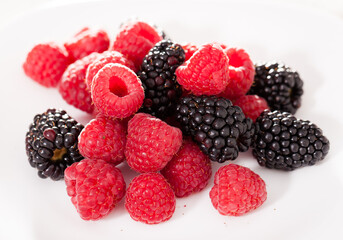 handful of raspberry and blackberry berries on white background