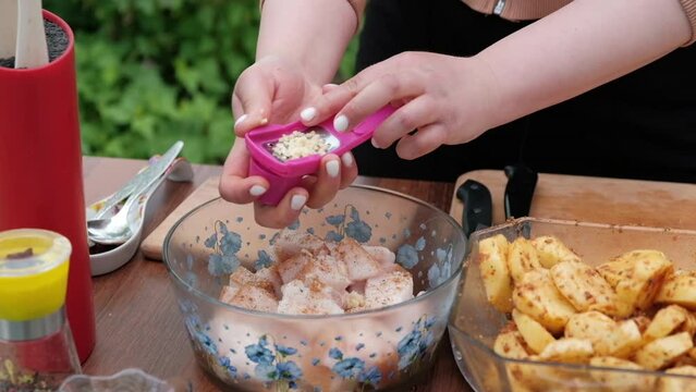 Close-up of women's hands slicing garlic on a grater. Prepare marinade for pork fat. Cooking in nature