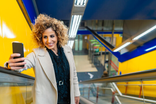 woman going up the escalator while using her smartphone
