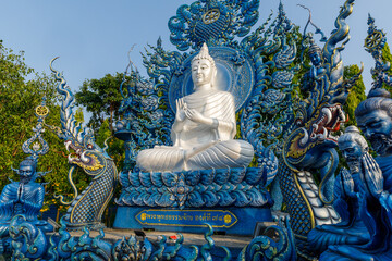 white buddha on a blue background meditating at Wat Rong Suea Ten Chiang Rai