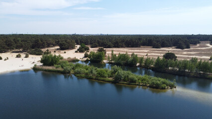 Aerial view of lake surrounded by growing bushes and sandy beach in Belgium - obrazy, fototapety, plakaty