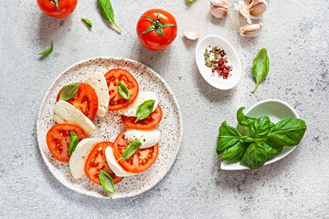 Fototapeta na wymiar Caprese salad with juicy tomatoes, fresh mozzarella and pesto. Concept for a tasty and healthy appetizer, flat lay. Italian food, cuisine.