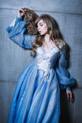A blond girl is posing in a soft blue dress with a sumptuous tulle skirt.