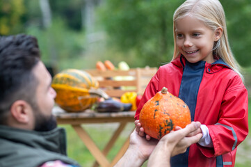 Dad and daughter sorting the pumpkings in the yard
