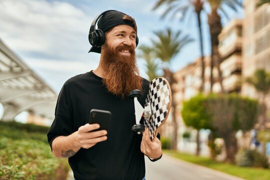 Young irish skater man using smartphone and headphones at the city.