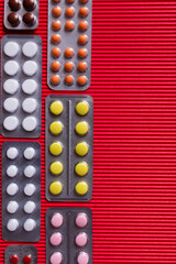 top view of blister packs with different pills on crimson textured background.