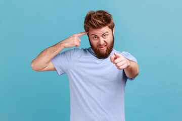 Hey, you are kidding. Portrait of bearded man with surprised face holding finger near head and...