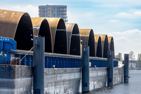 Closeup of barges with monopiles in an industrial harbor in Roermond