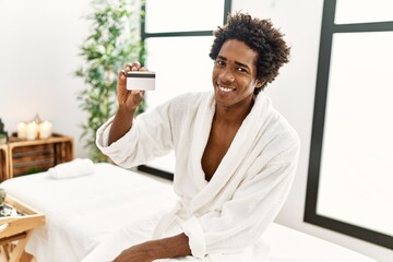 Obraz na płótnie Canvas Young african american man smiling confident holding credit card at beauty center