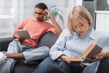 young african american man and blonde woman reading books.