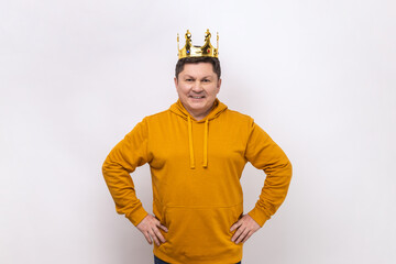 Man egoistically looking at camera and smiling, posing with crown on head, pretending to be king,...