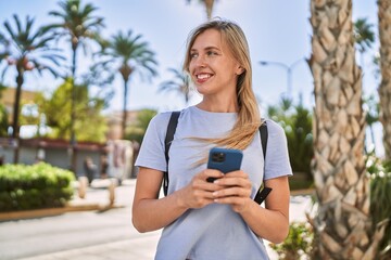 Young blonde woman smiling confident using smartphone at park