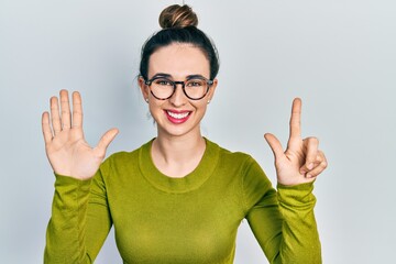 Young hispanic girl wearing casual clothes and glasses showing and pointing up with fingers number seven while smiling confident and happy.