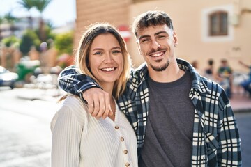 Young man and woman couple hugging each other standing at street