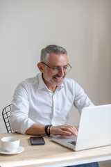 Smiling man in glasses typing on laptop