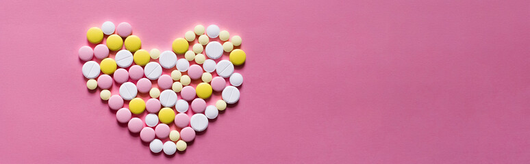 flat lay view of different round pills in shape of heart on pink background, banner.